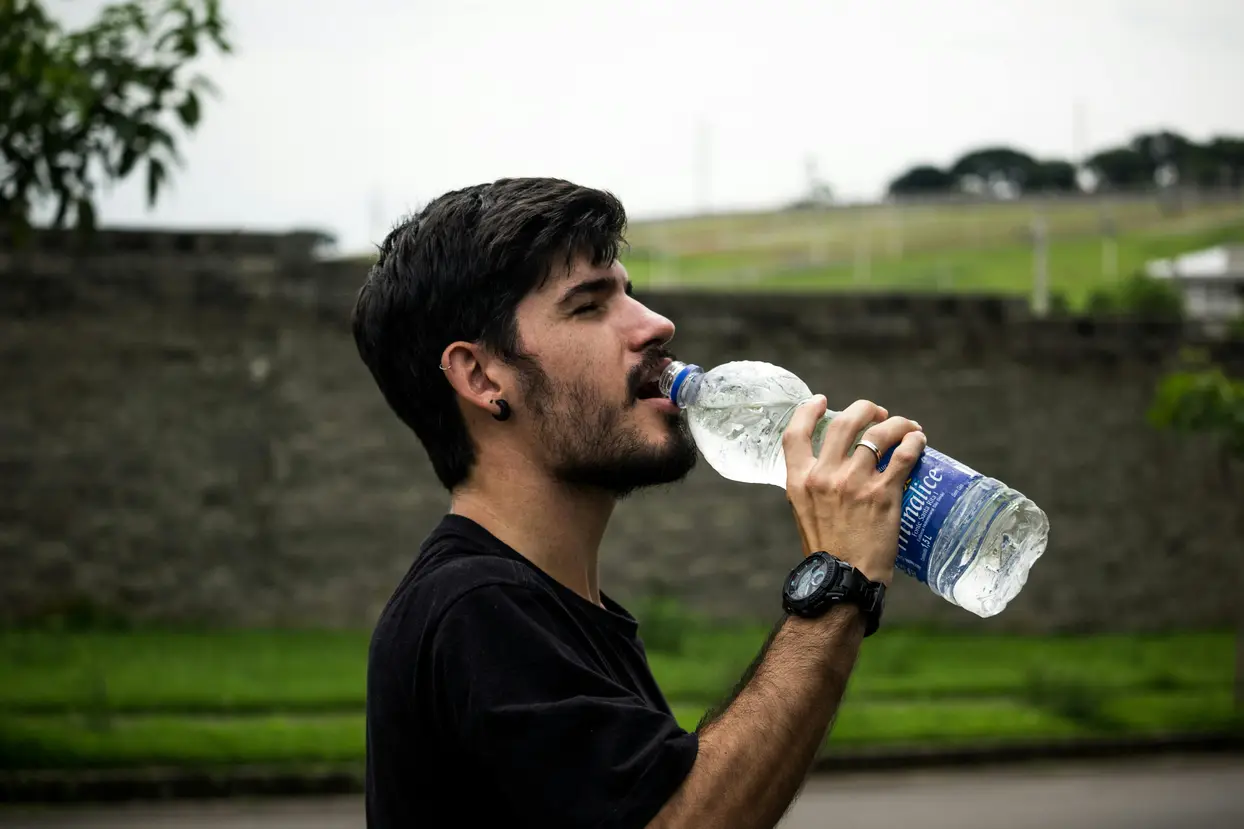 Hombre tomando agua desde botella de plástico